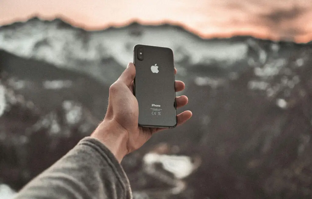 hand holding iphone with mountain behind