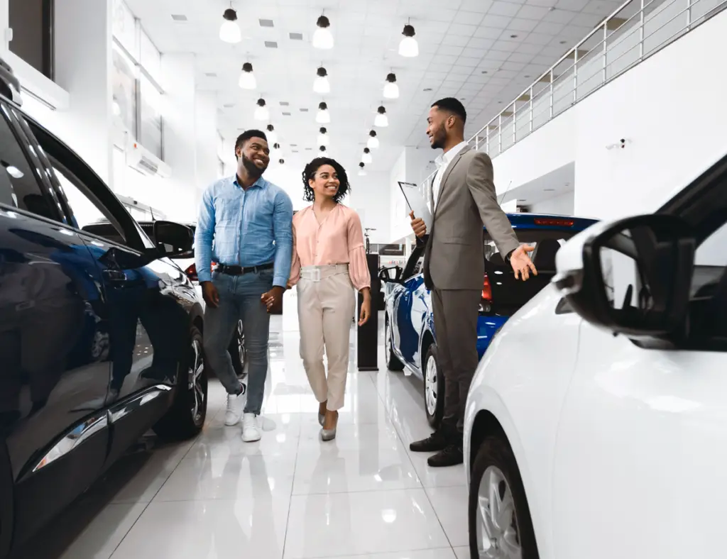 man doing car sales with two customers