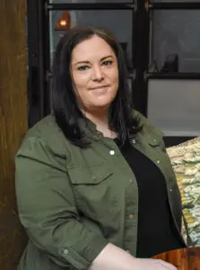 a woman with dark hair wearing a green jacket