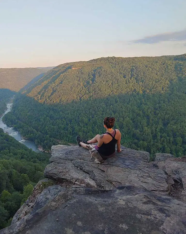 a woman sitting on a rock overlooking a valley