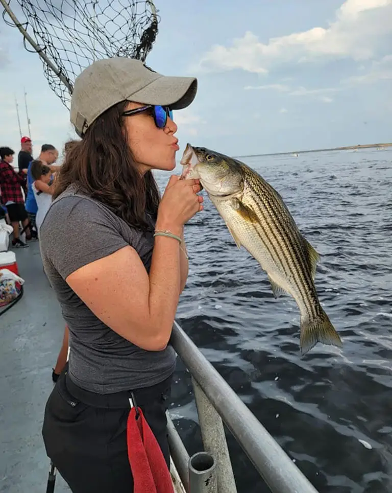 a woman kissing a fish on a boat