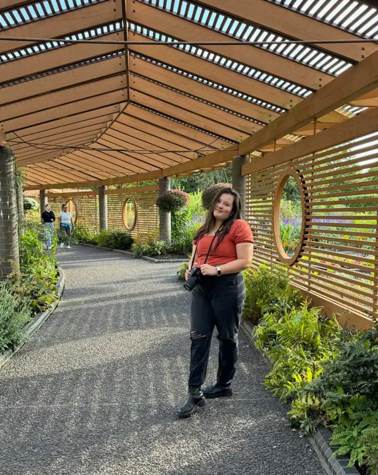 a woman standing under a pergola