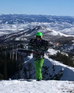 a person in green ski gear on a snowy mountain