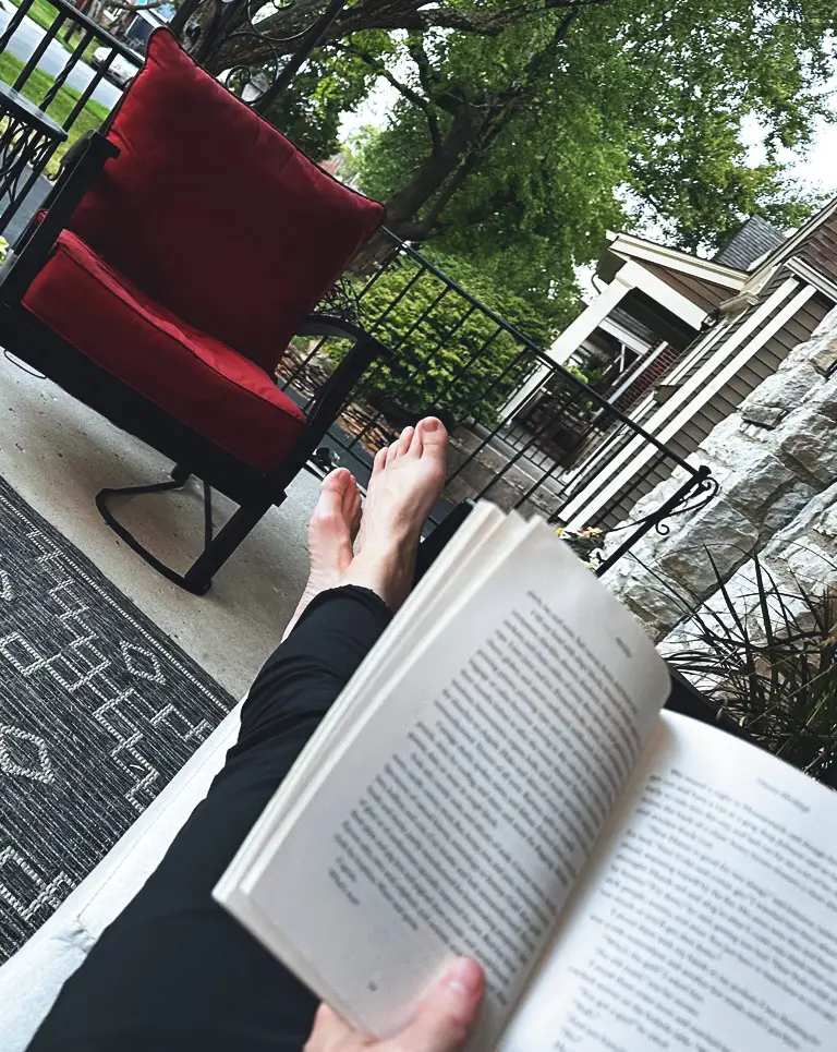 a person's feet and a book on a porch