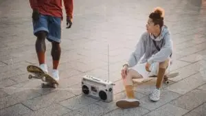 a group of people sitting on the ground with a radio and skateboard