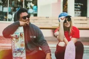 a man and woman sitting on a bench with skateboards